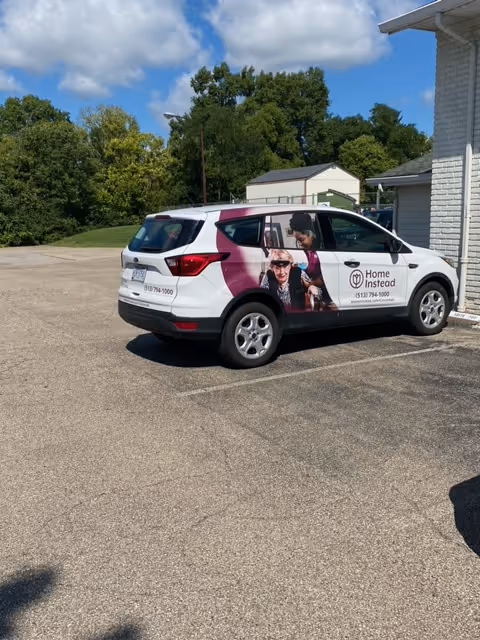 White Home Instead van with promotional wrap parked beside a building.