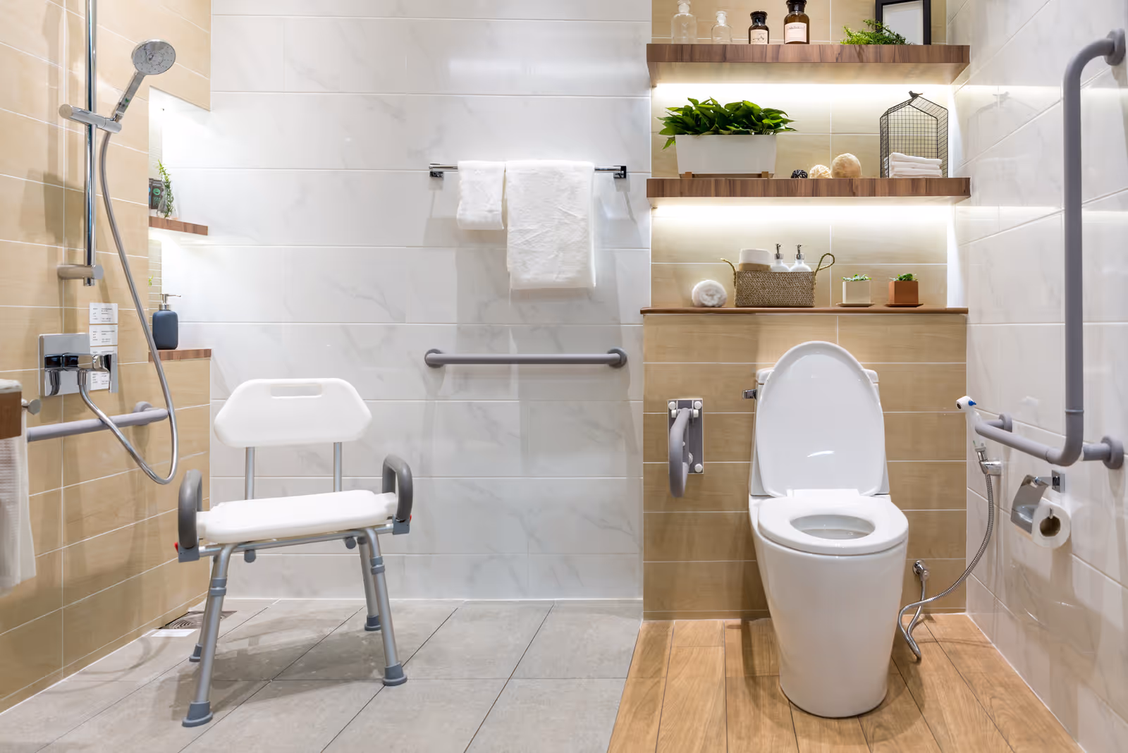 Accessible bathroom with shower, toilet, grab bars, and a transfer chair.
