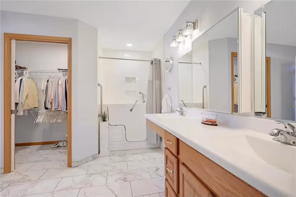 Bright bathroom with double-sink vanity, large mirrors, and a walk-in shower.