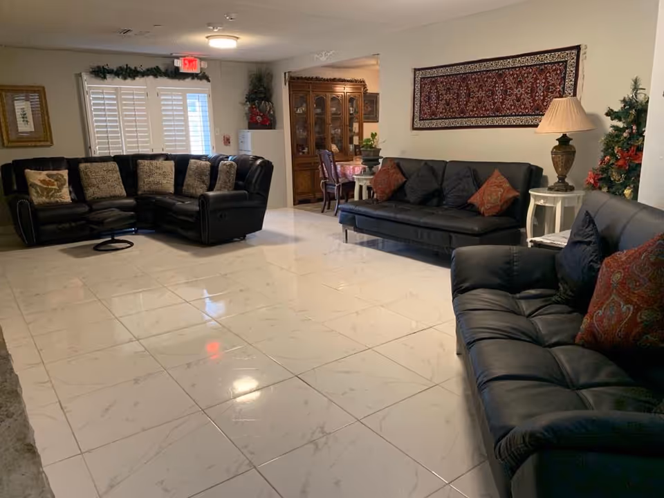 A spacious common living room with black leather sofas and holiday decorations.