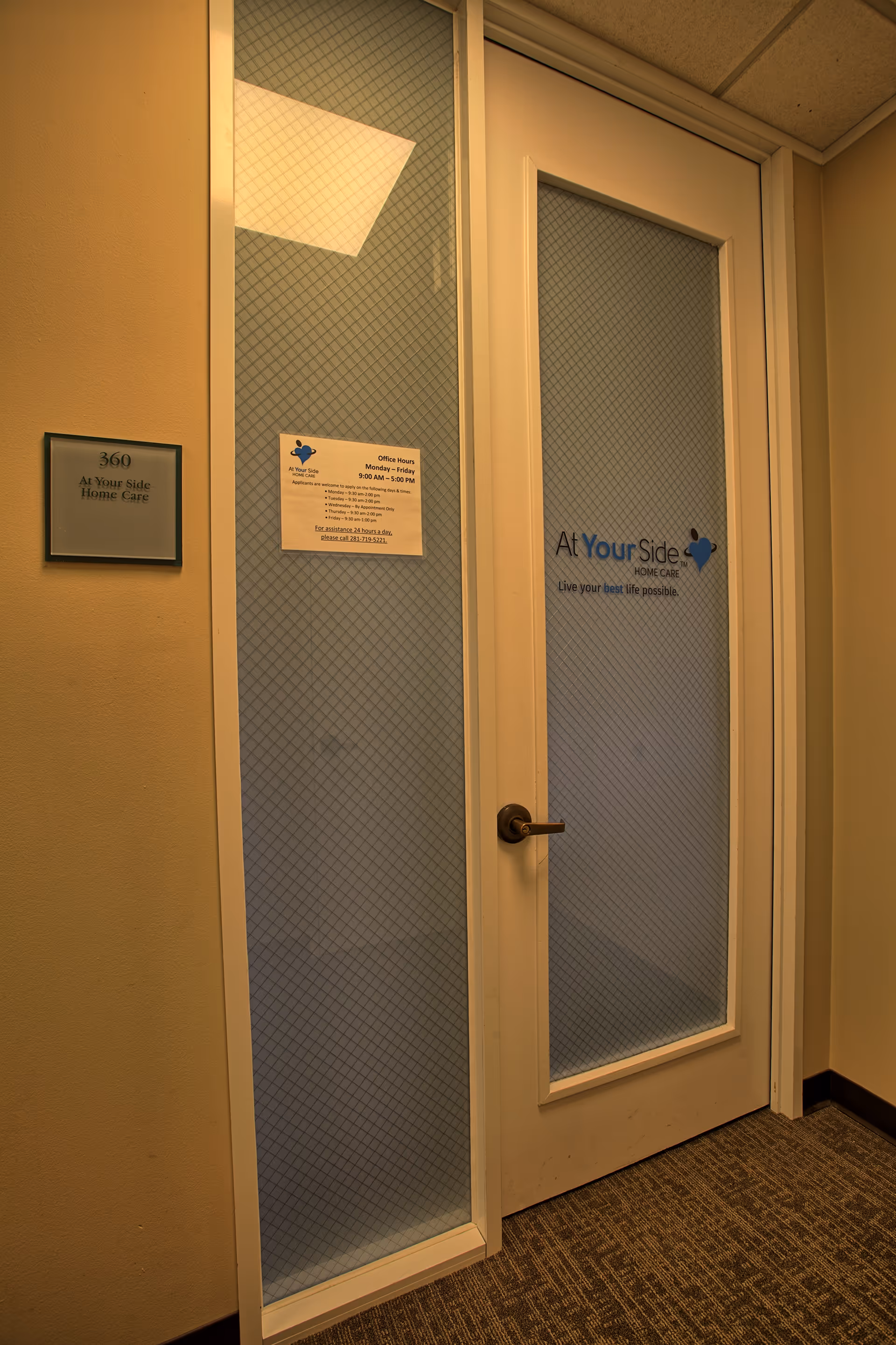 Interior hallway with frosted glass doors labeled At Your Side Home Care and a hallway plaque.