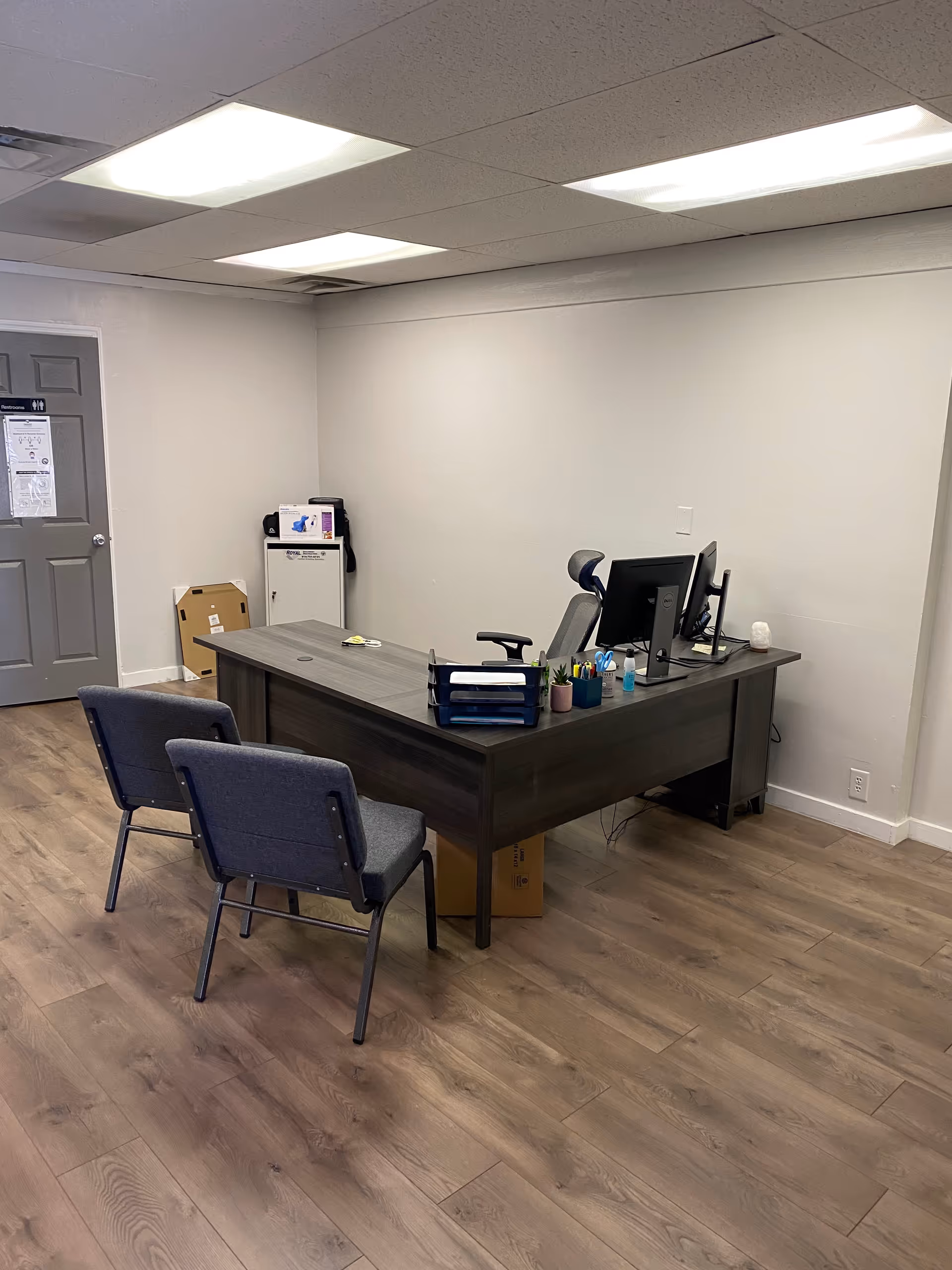 Office desk with computer and chairs in a small reception area.