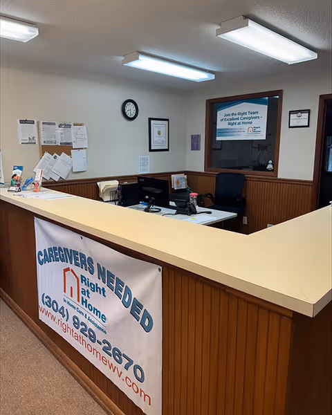 Front desk reception area with a caregiver banner, computers, and bulletin boards.