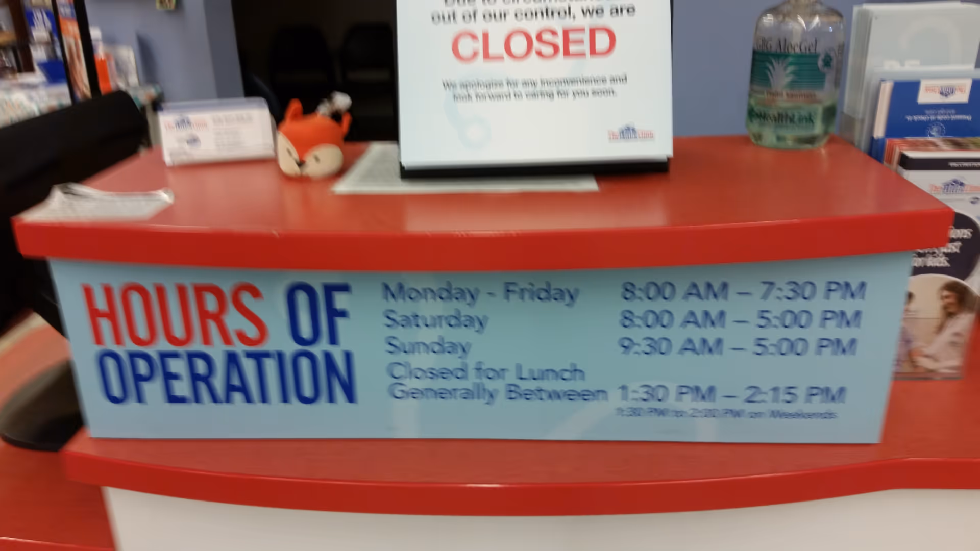 Red reception desk with a large Hours of Operation sign and a closed notice.