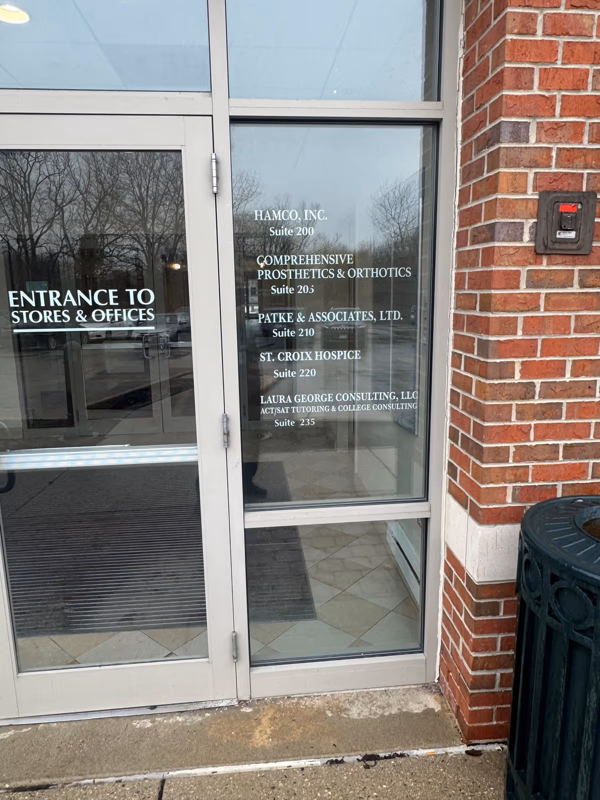 Glass entrance door with suite listings on a brick building exterior.