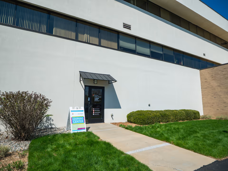 Exterior view of Total Spectrum ABA building entrance with sign and landscaping.