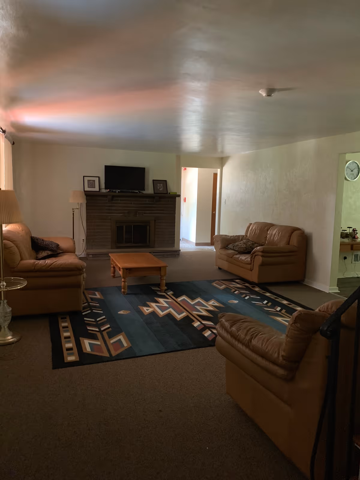 Living room with tan sofas, a fireplace, TV, and a geometric rug.