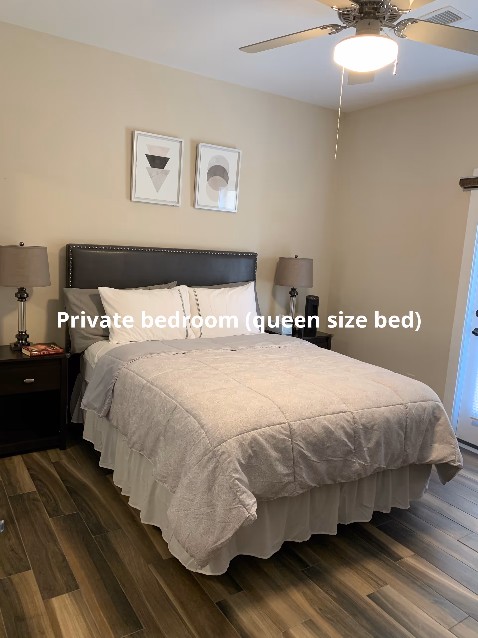 Private bedroom featuring a queen-size bed, two nightstands, lamps, wall art, and ceiling fan.