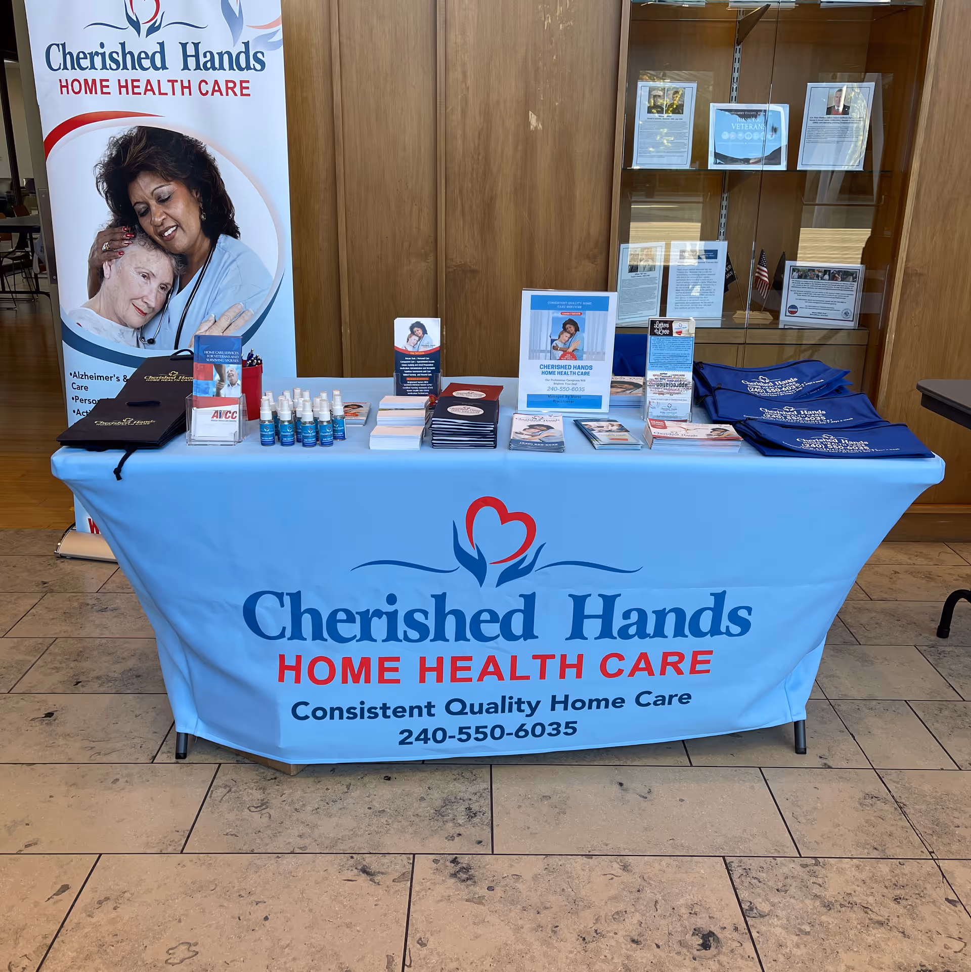 Promotional table with Cherished Hands Home Health Care banners and brochures inside a lobby.