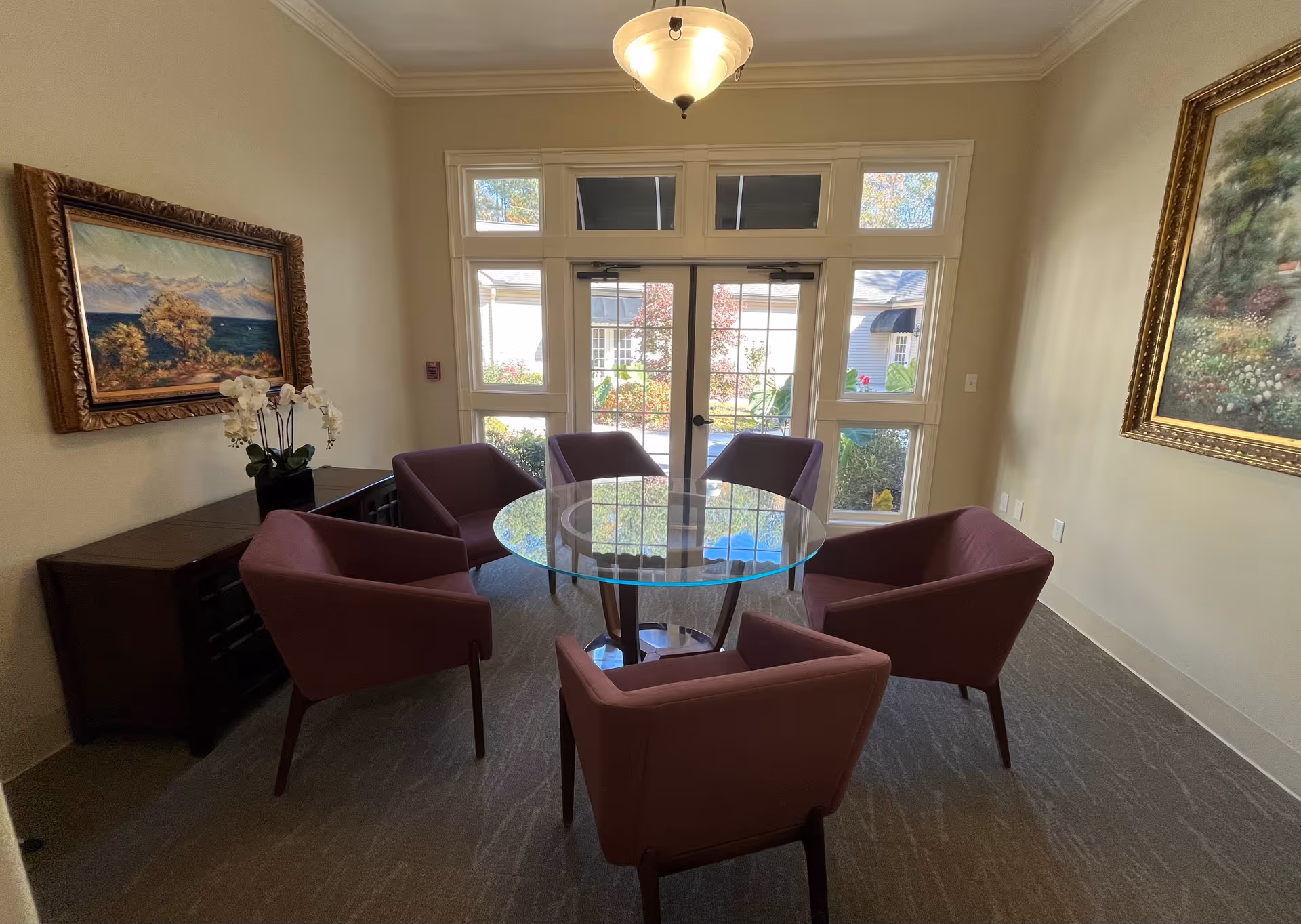 Indoor lounge with a round glass table and five purple chairs.