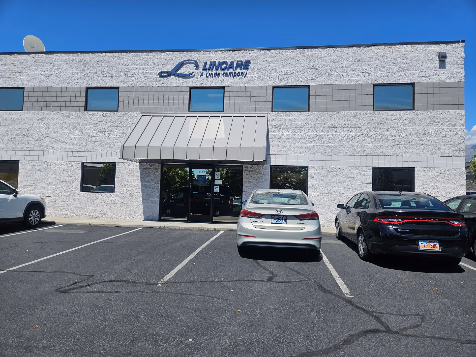 Exterior view of LINCARE facility with a white brick facade, entrance, and parked cars.