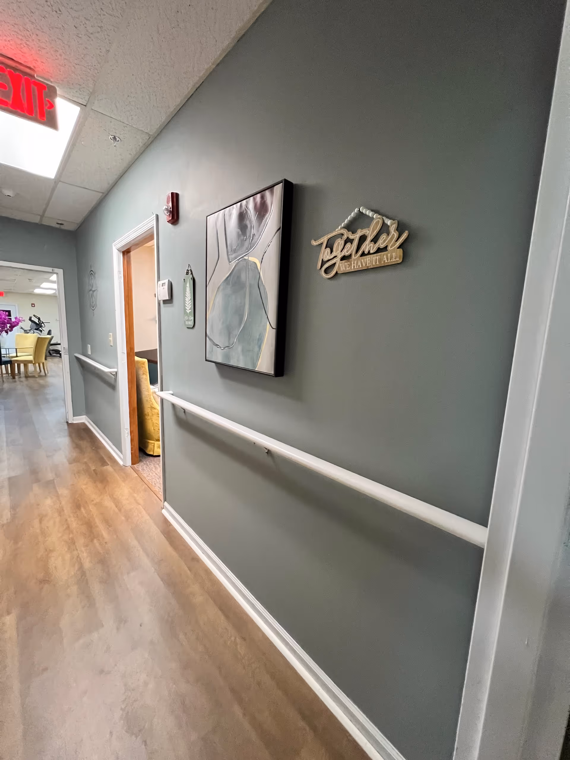 Interior hallway of a senior living facility with wall art and handrail