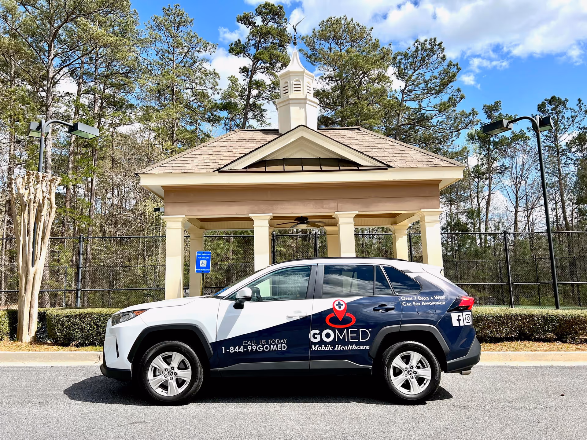 GOMED Mobile Urgent Care SUV parked in front of a beige pavilion with columns.