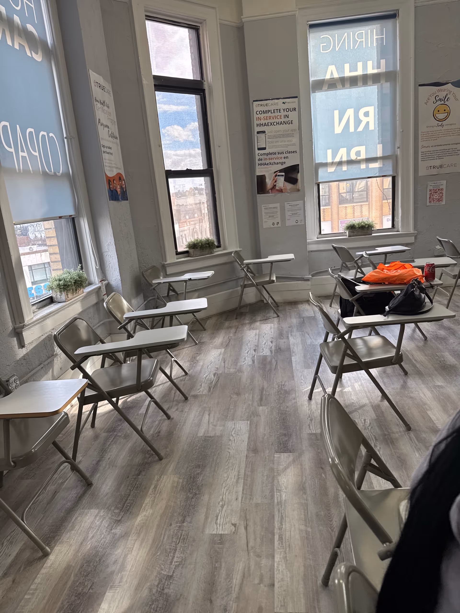 Bright interior room with foldable desks and chairs arranged along the windows.