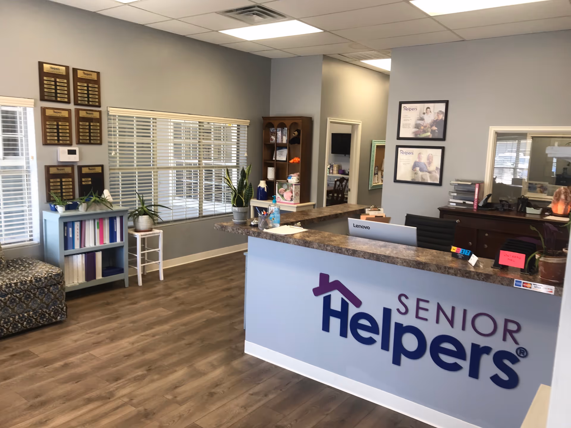 Reception desk with Senior Helpers branding, plants, and office decor inside a senior living facility.