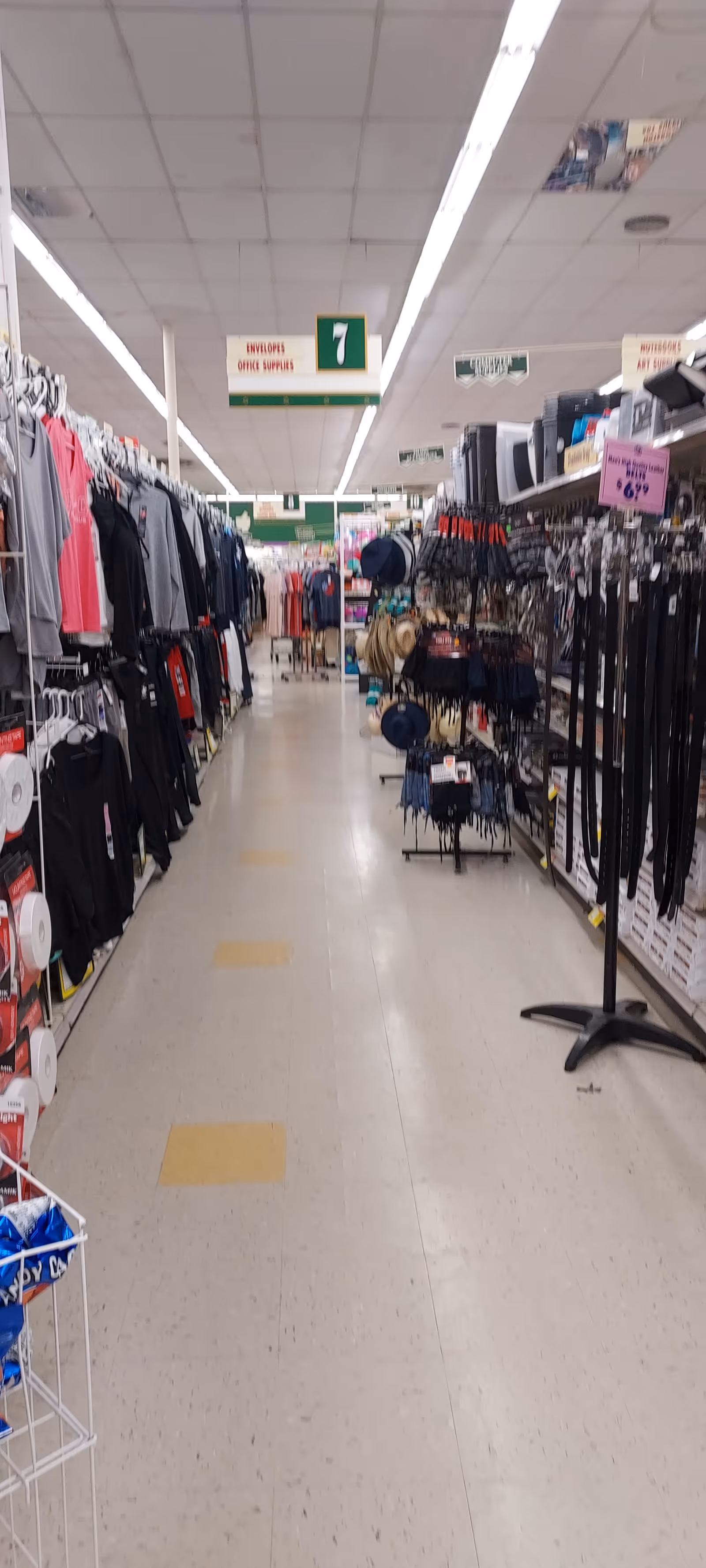 An aisle in a retail store with clothing racks and accessories on both sides.
