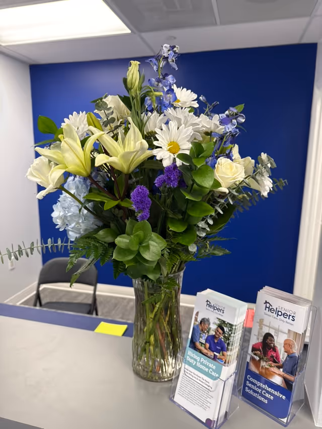 A vase of mixed flowers on a reception desk in a blue facility lobby.