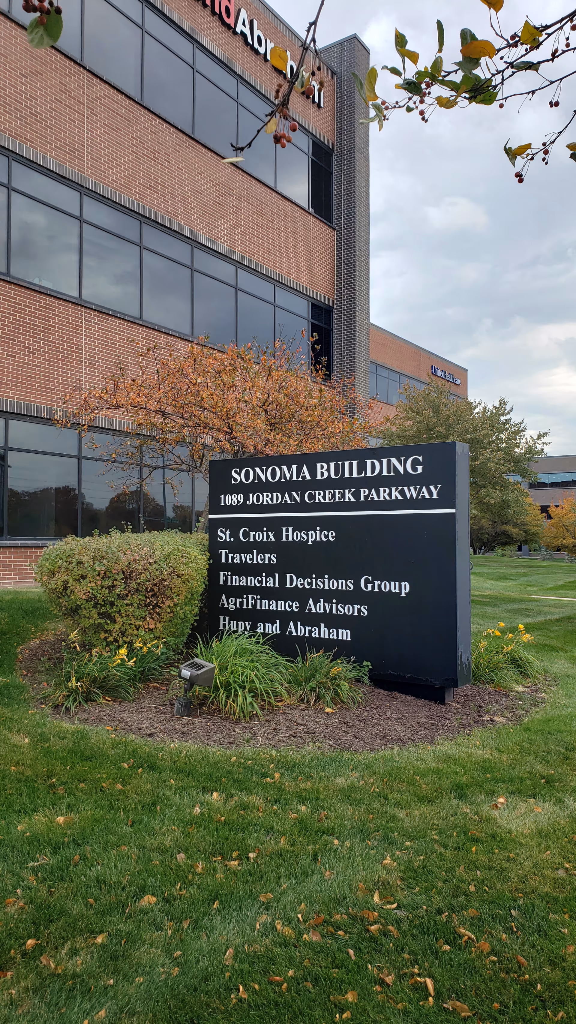 Exterior view of a brick office building with a large sign and landscaped front yard.