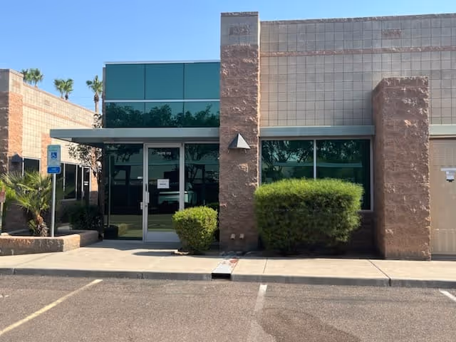 Front view of Serengeti Care facility entrance with glass doors and shrubs.