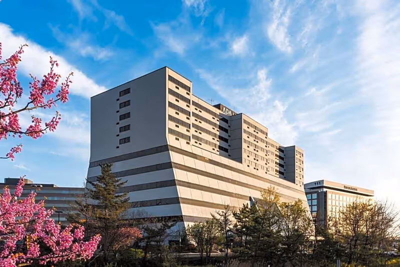 Exterior view of a modern BAYADA Adult Nursing building with trees and pink blossoms.