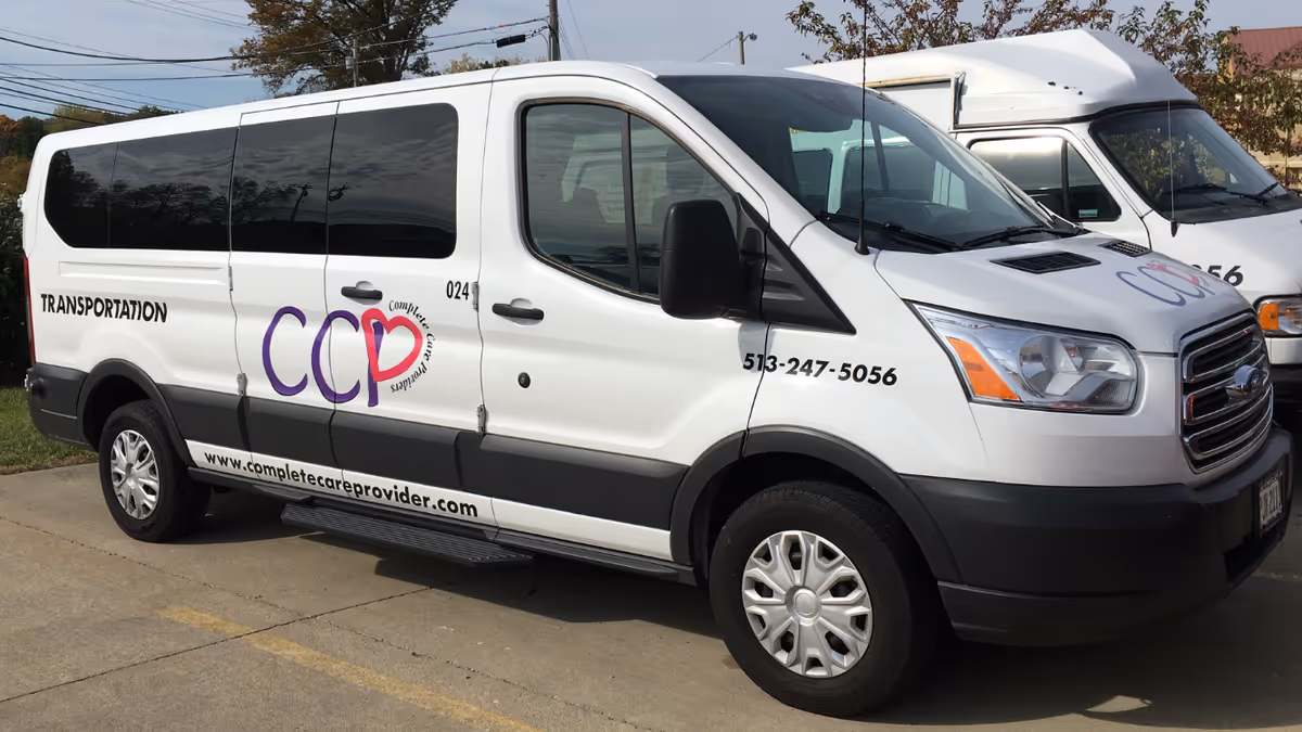 White transportation vans with Complete Care Providers logo parked in a lot.