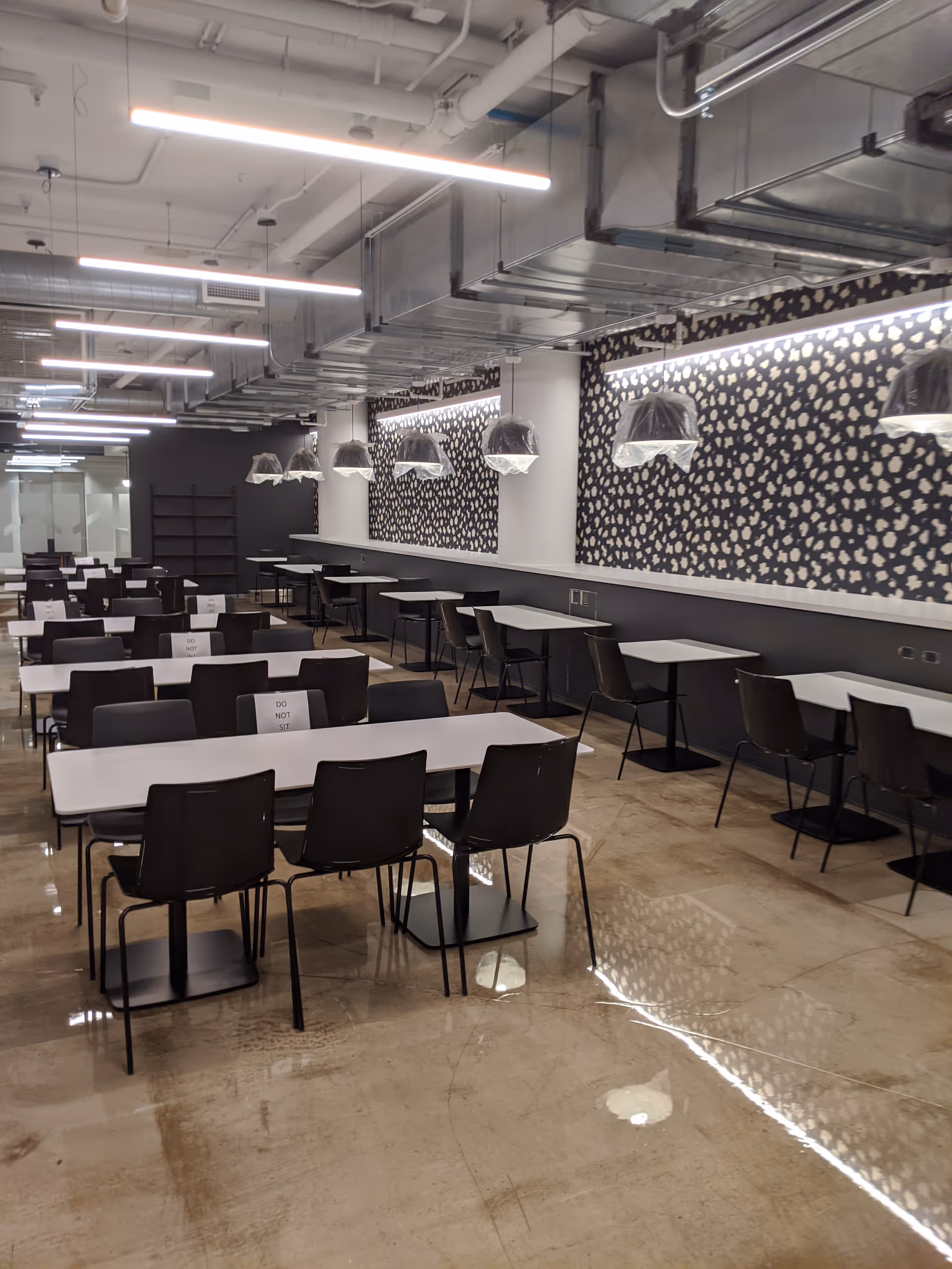 Empty dining room with rows of tables, black chairs, and patterned walls.