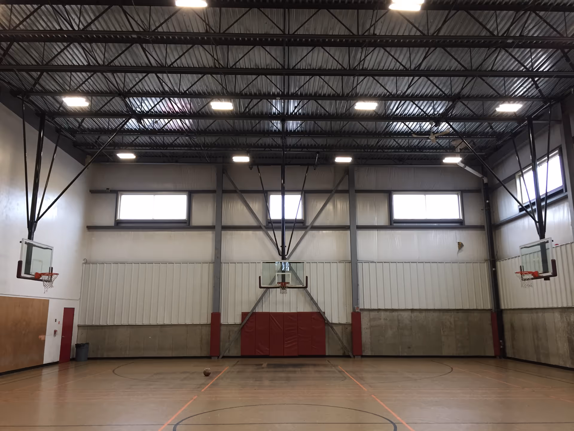 Empty indoor basketball gym in a senior living facility with hoops and wooden floor.