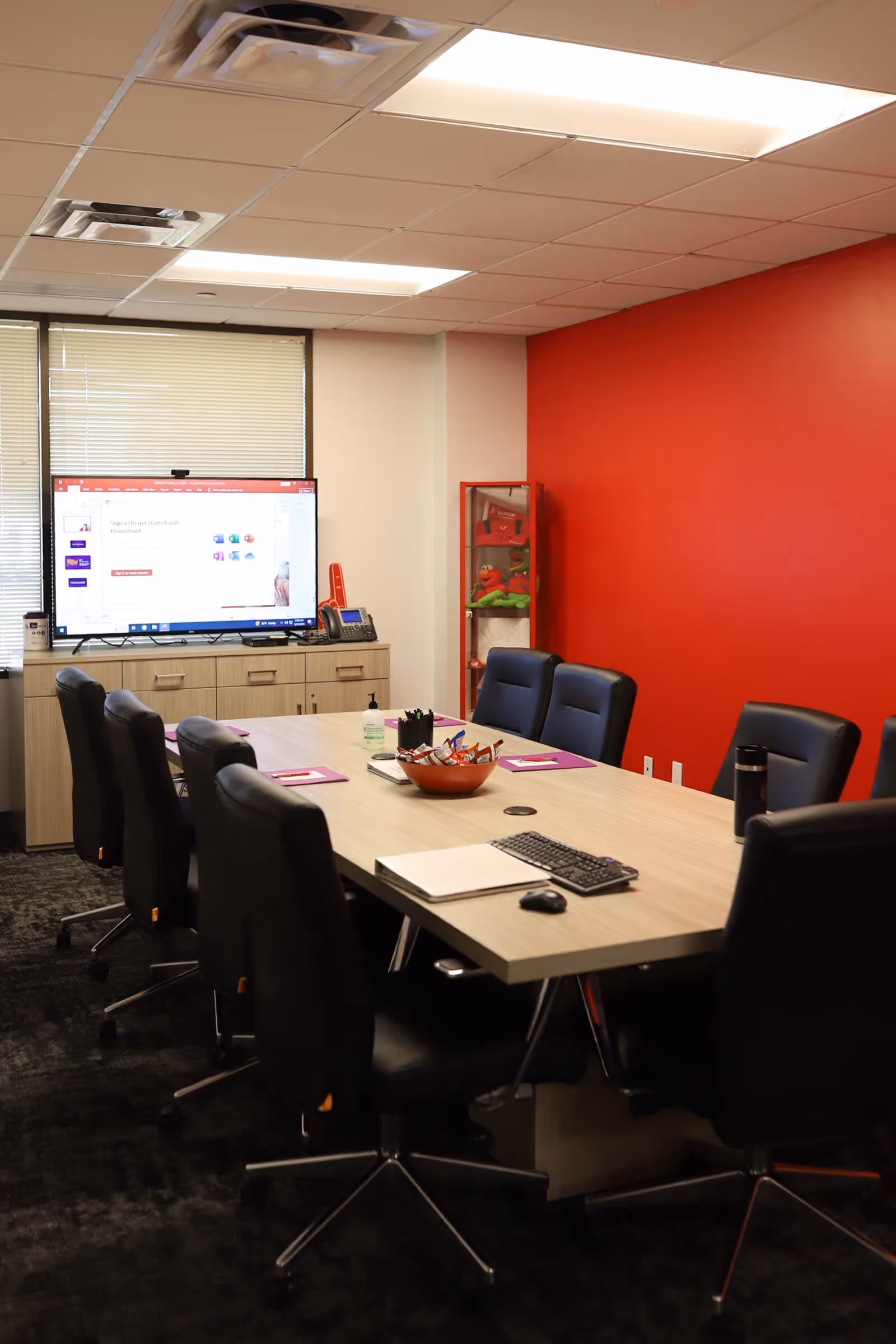 A BAYADA Assistive Care conference room featuring a long table, black chairs, and a large screen.