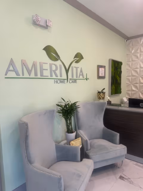 Reception lobby with two light-blue armchairs, a potted plant, and Amerivita Home Care sign.