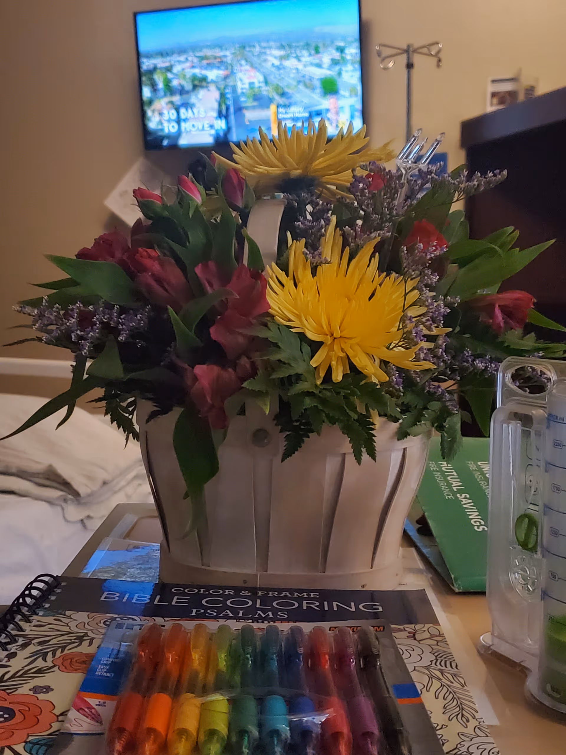 Bouquet of yellow flowers and colorful markers on a bedside table in a cozy room.