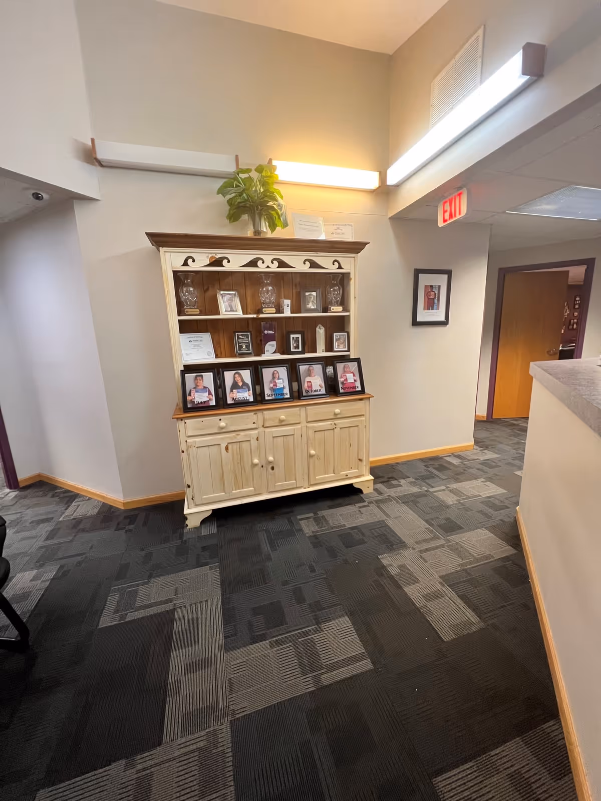 Hallway interior featuring a cream display cabinet with framed photos and a plant on top.