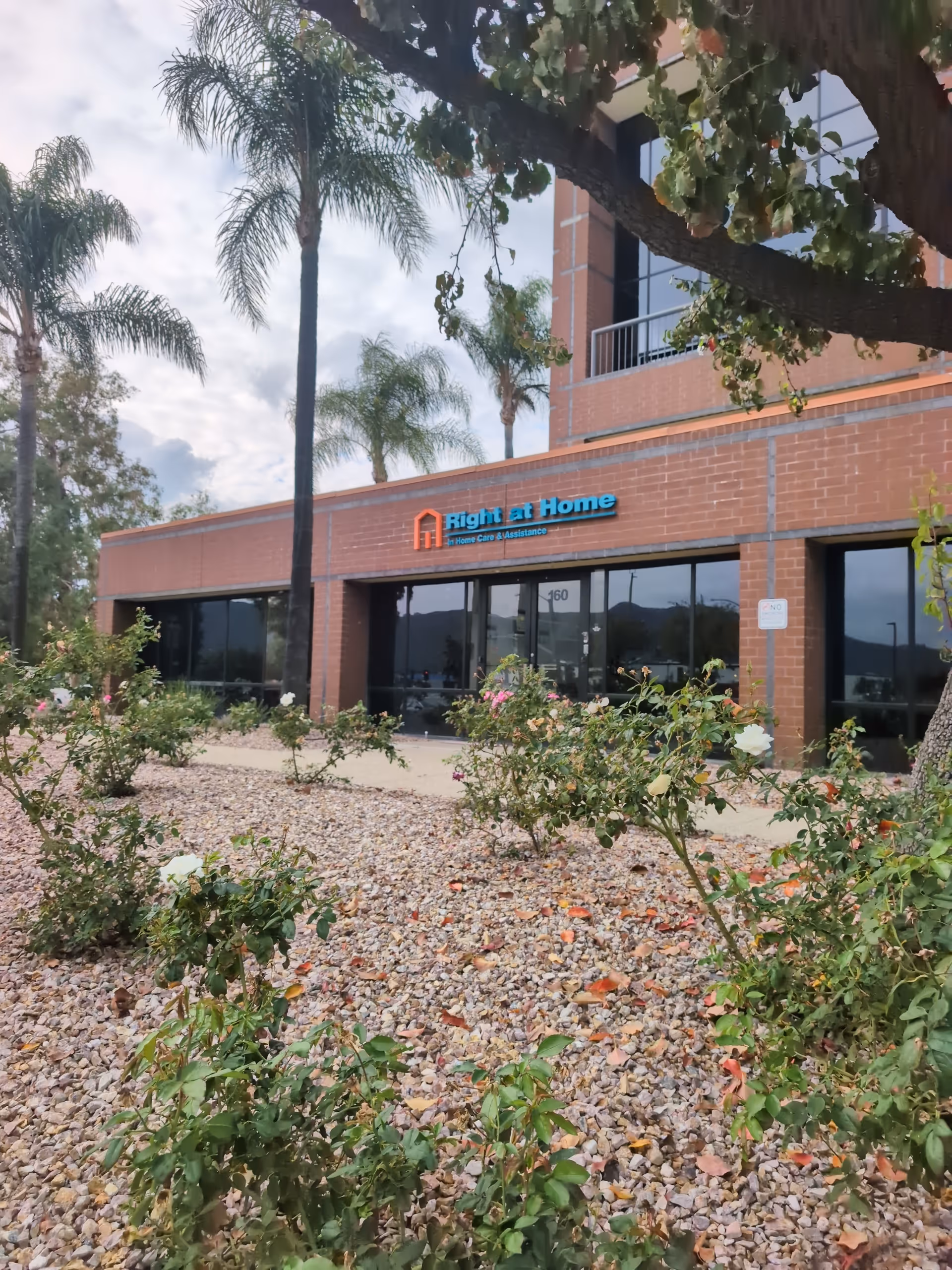 Exterior view of Right at Home senior care facility with palm trees and landscaping.