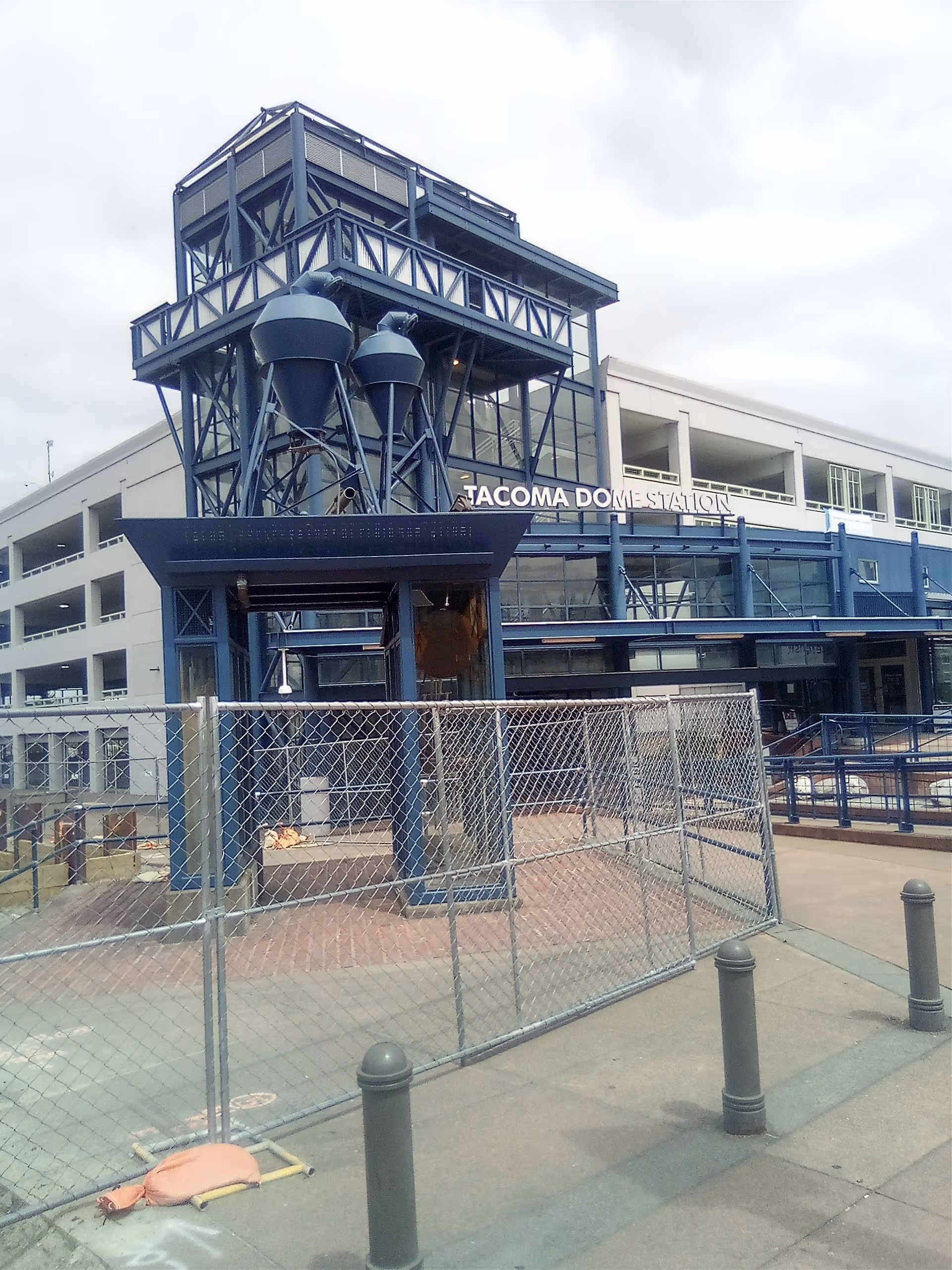 Exterior view of Tacoma Dome Station with blue framework and chain-link fence.
