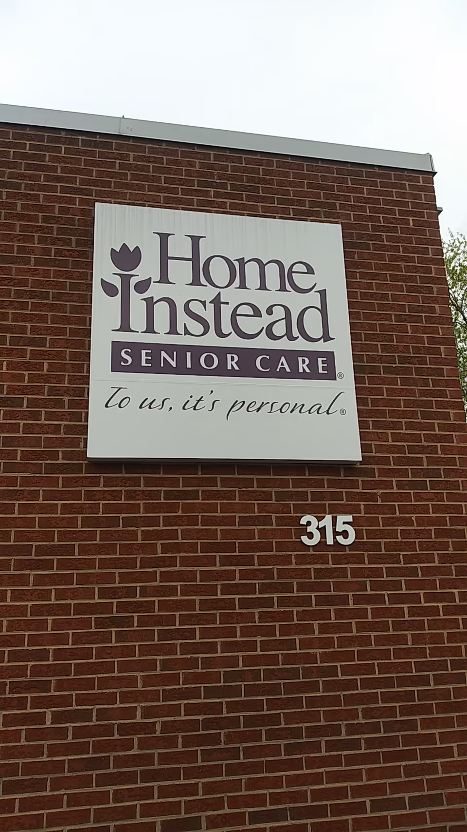 Sign for Home Instead Senior Care mounted on a brick building exterior.