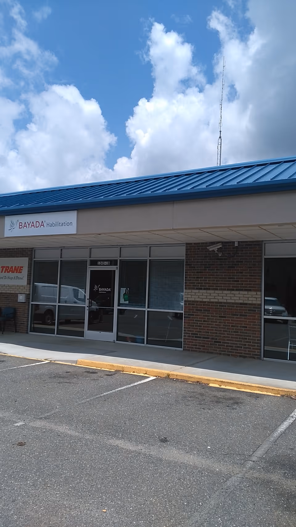 Exterior storefront of BAYADA Habilitation with glass doors and a blue metal awning.