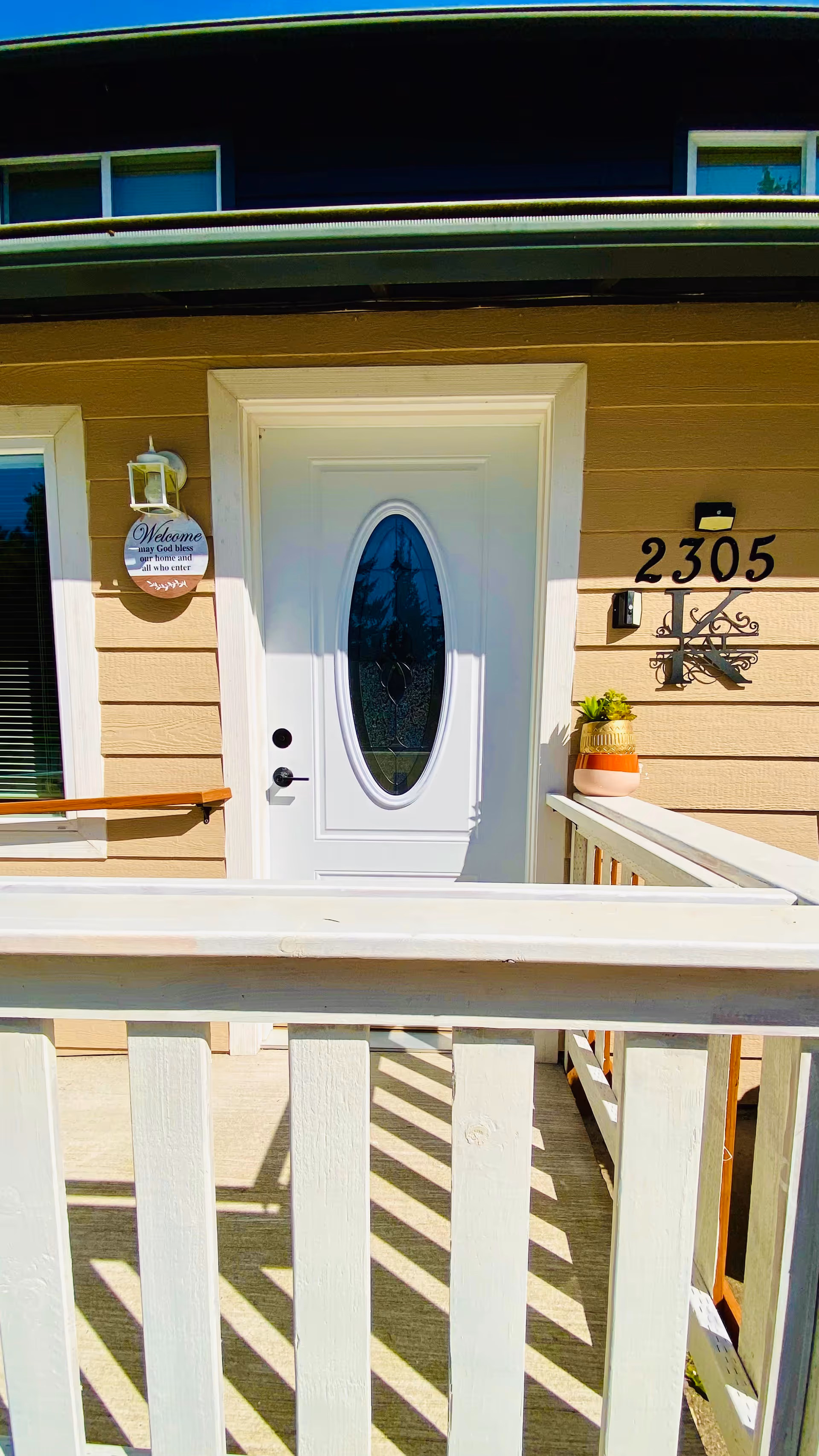 Entrance of a beige senior living home with a white front door and railing.