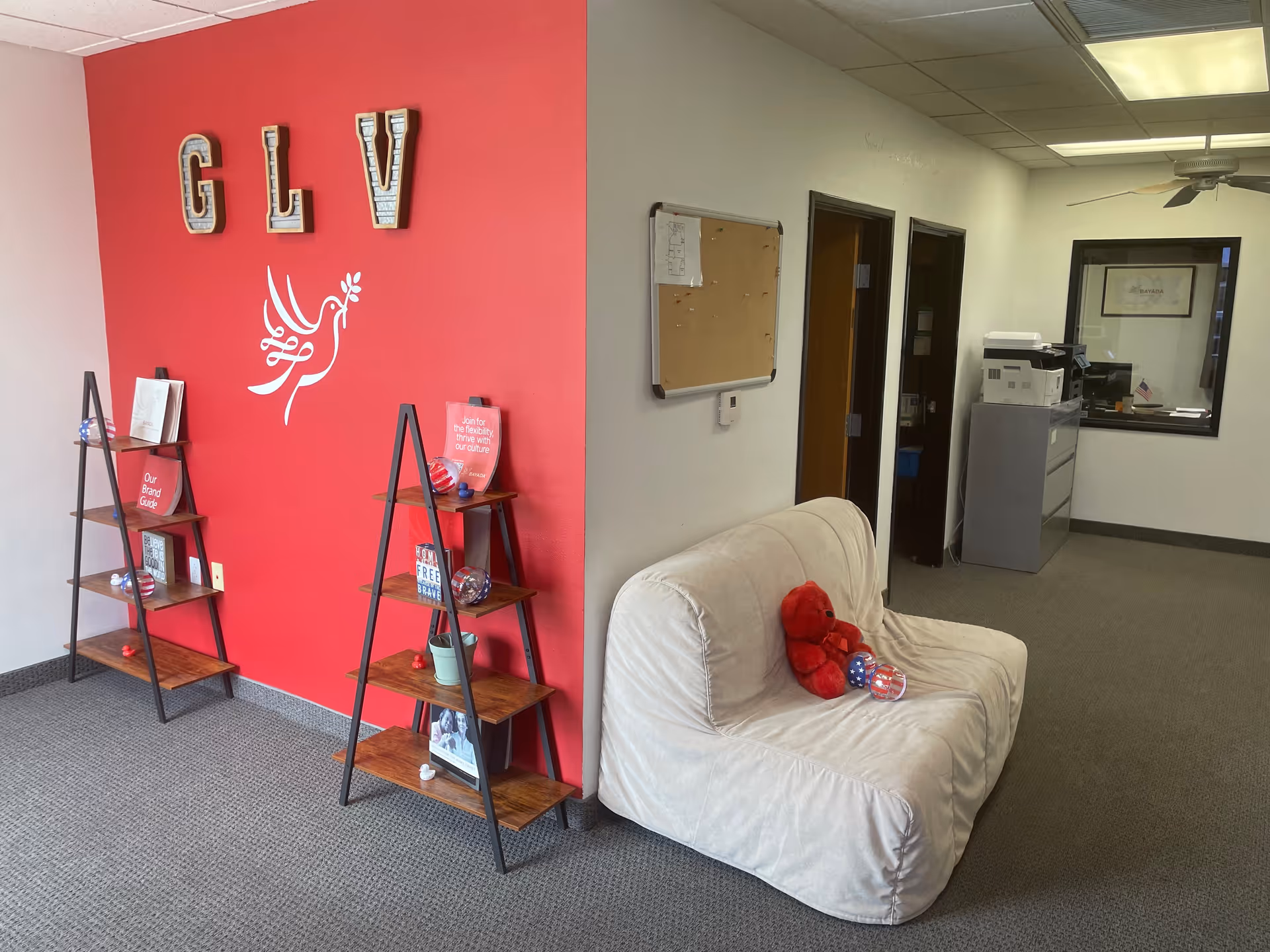 Bright pink wall with shelves and a beige couch in a facility lobby.