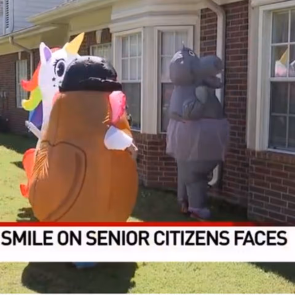Two large inflatable cartoon characters stand outside a brick house.