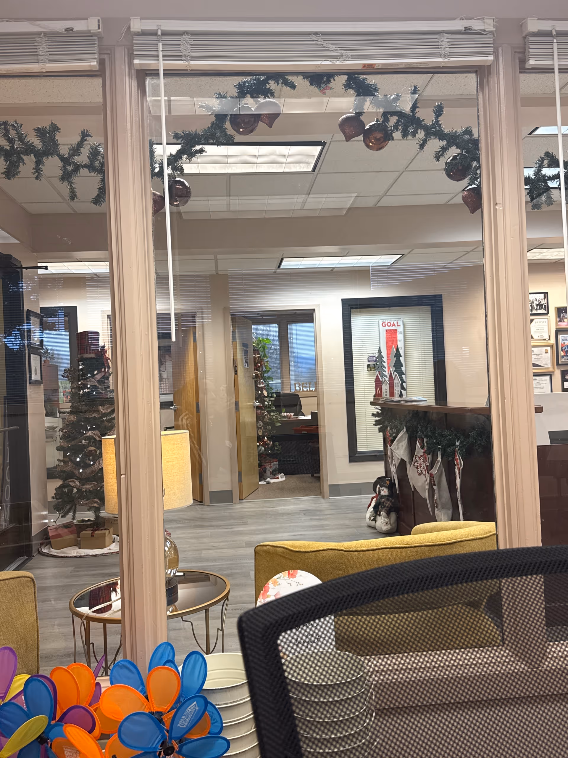 Holiday-decorated indoor senior living lobby with seating, glass walls, and festive garlands.