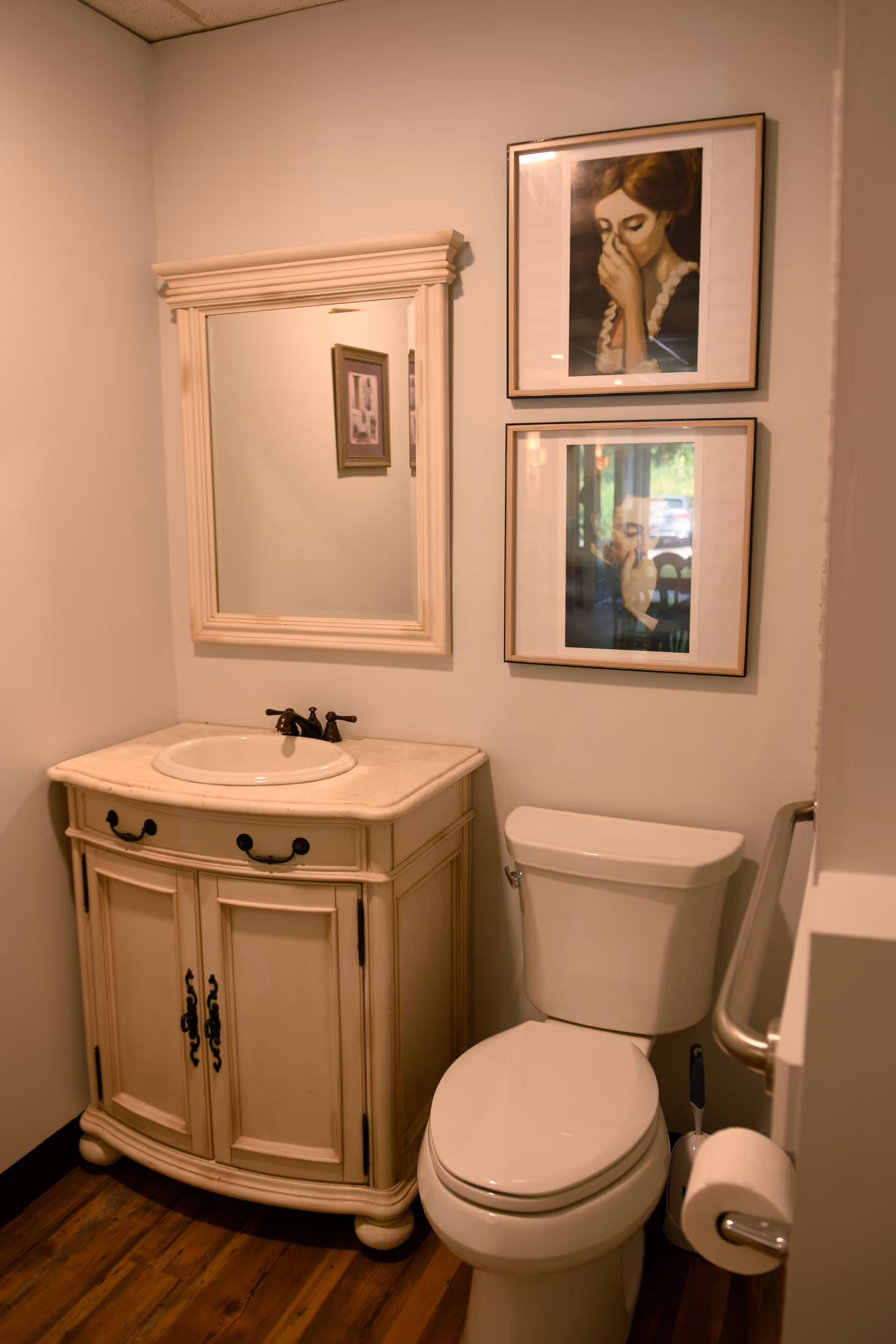 Small bathroom with vanity, mirror, toilet, and framed wall art.