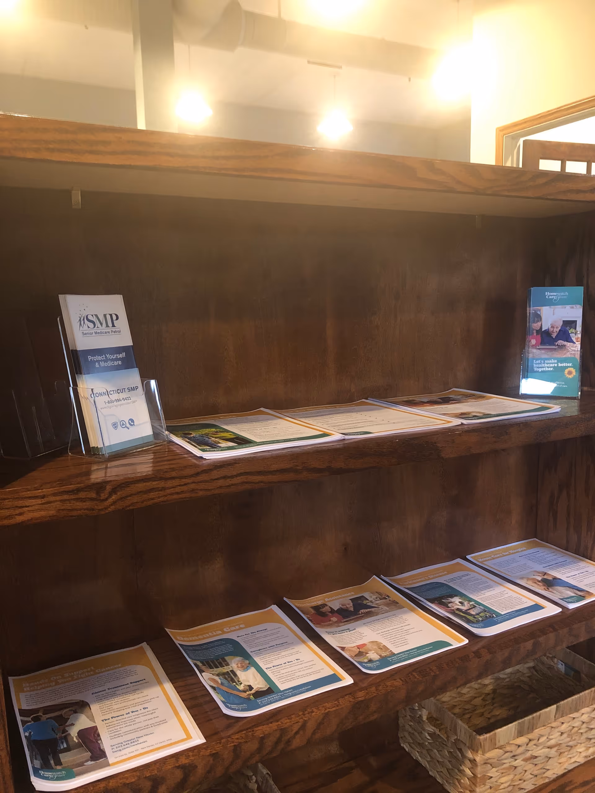 Wooden brochure shelf with pamphlets in a well-lit lobby.