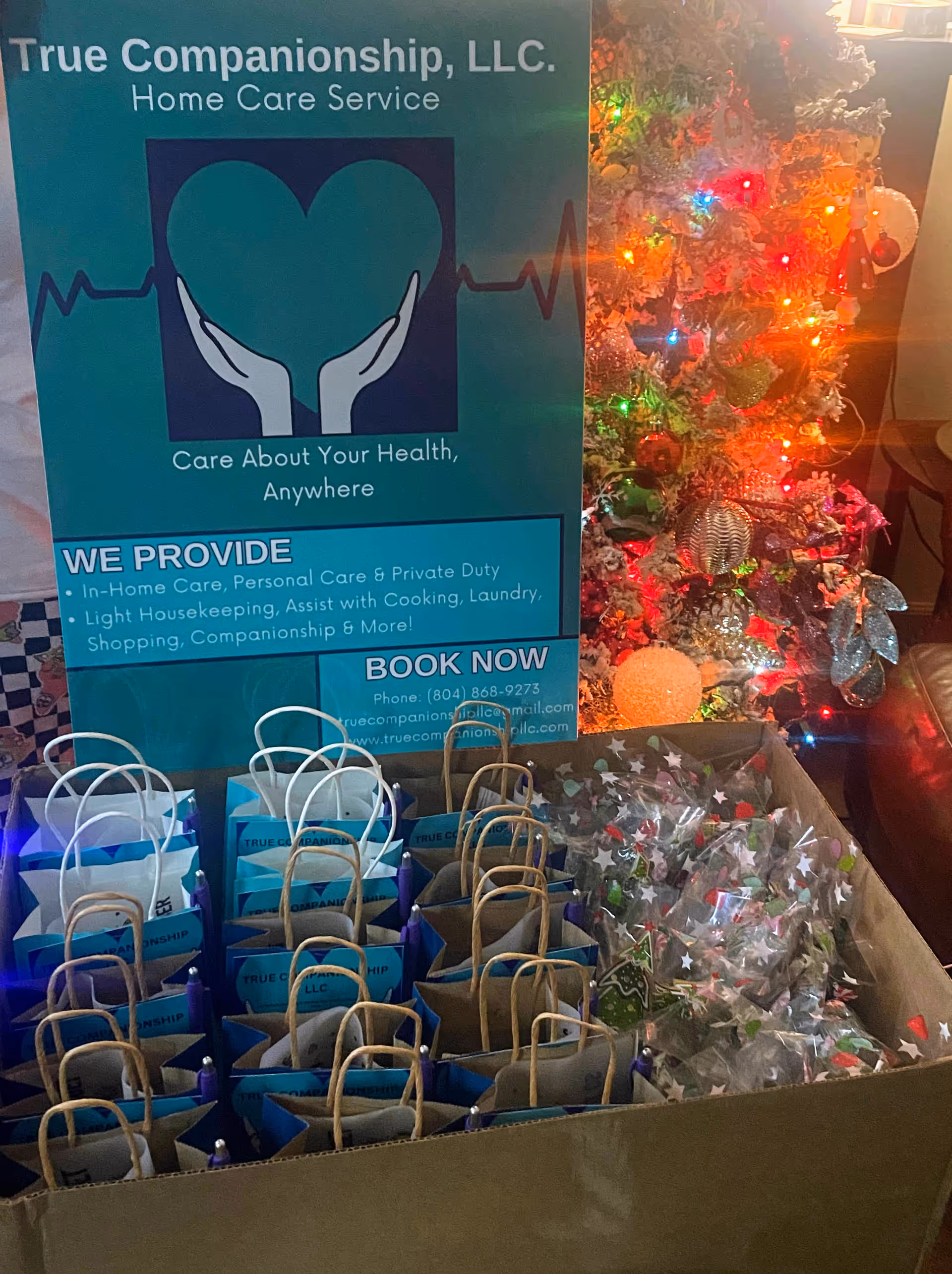 Promotional sign for True Companionship LLC with gift bags near a Christmas tree