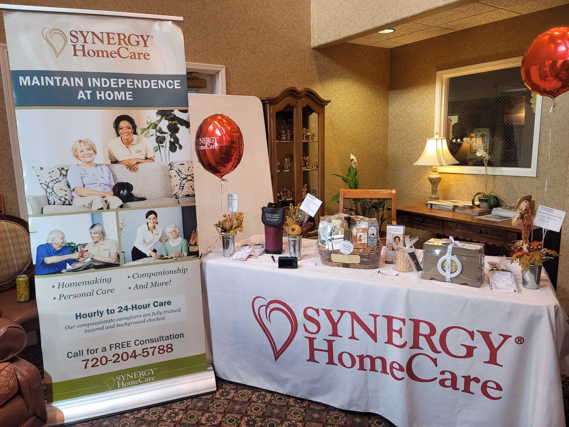 SYNERGY HomeCare promotional display in an interior lobby with banners and a table.