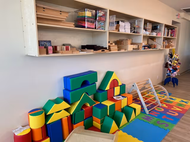 Colorful foam blocks, mats, and shelves fill a bright indoor activity room.