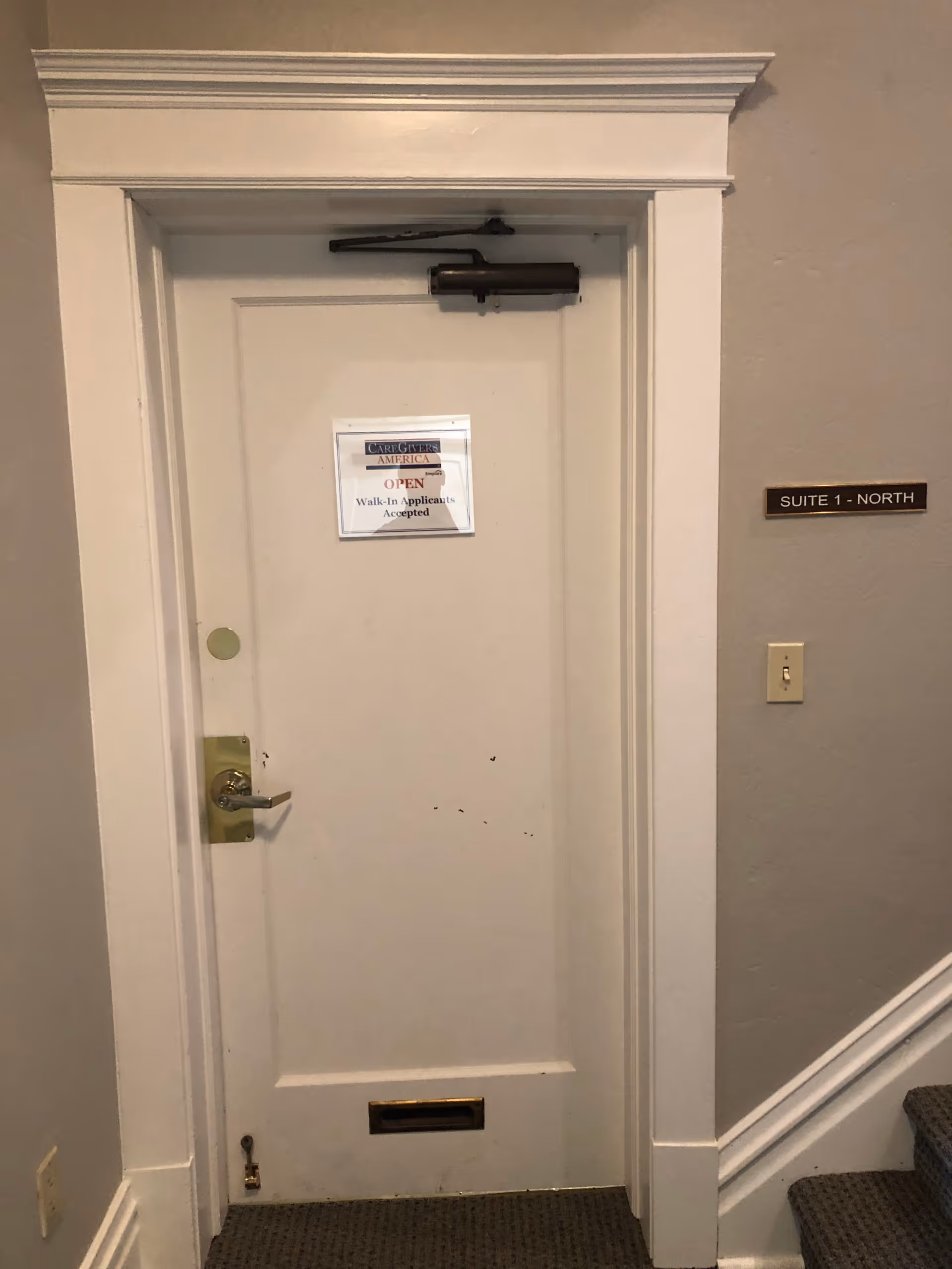 Interior hallway with a white door labeled CareGivers America and Suite 1 - North plaque.