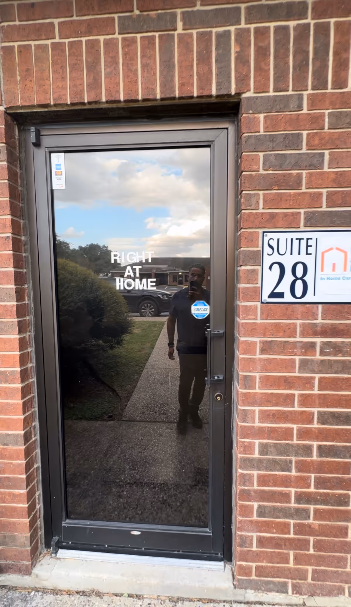 Brick exterior entrance with glass door labeled Right at Home and Suite 28 sign.