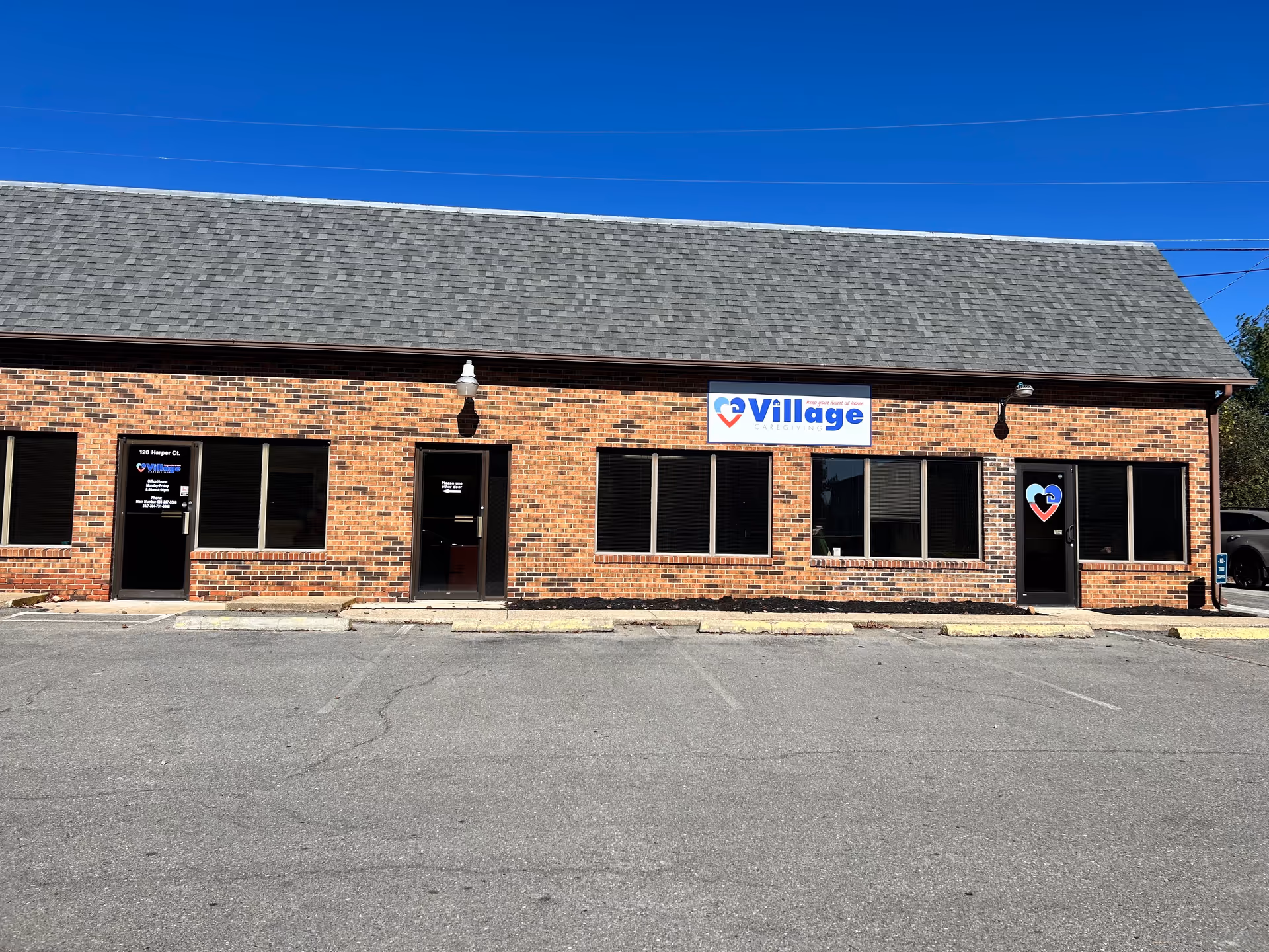 Brick one-story facility exterior with multiple windows and Village Caregiving sign.