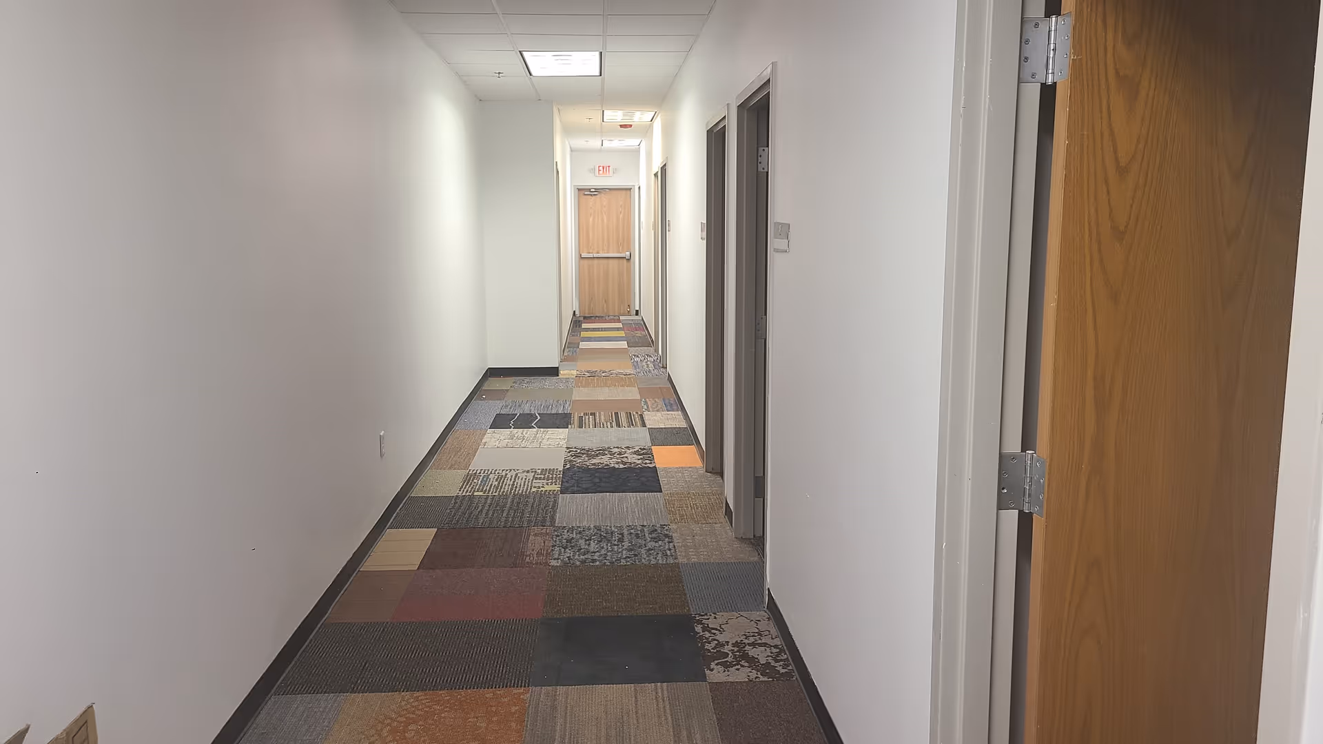 Narrow hallway in a senior living facility with patterned carpet and doors