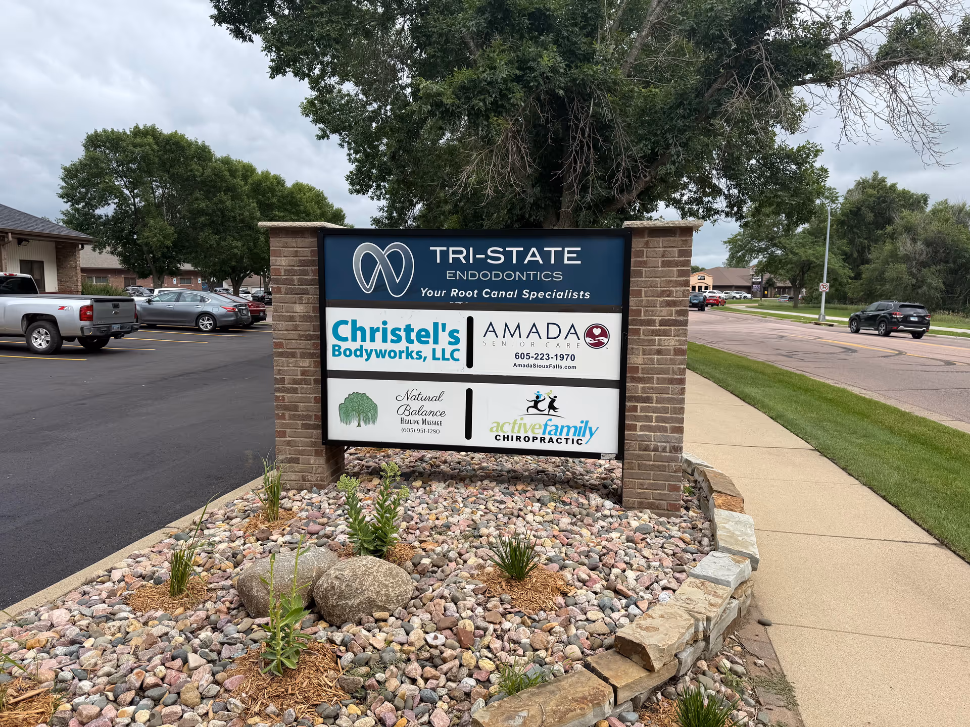Exterior sign board with Amada Senior Care and other business logos in a parking lot.