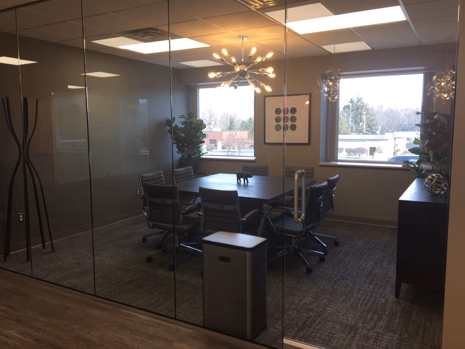 Glass-walled conference room with a long table, chairs, and large windows.